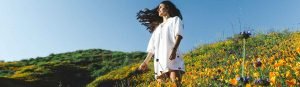 woman standing in field surrounded by flowers